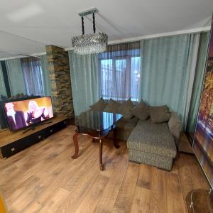 a living room with a table and a couch and a tv at Абзал in Karagandy
