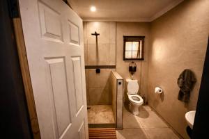 a bathroom with a toilet and a cross on the wall at ColtsRest in White River +17 photos