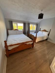 two beds in a room with wooden floors and windows at Magilligan Lodge in Bellarena Station