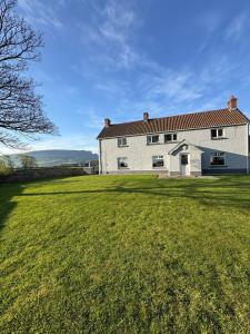 a large white house with a large grass yard at Magilligan Lodge in Bellarena Station
