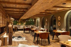 a restaurant with wooden ceilings and tables and chairs at Vila Muhr in Bohinj