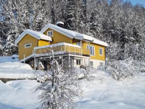 a yellow house in the snow with trees at Solhaug in Torpo