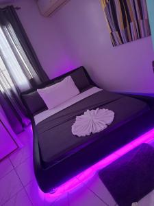 a bedroom with a bed with purple lights on it at Vacazure in Christ Church