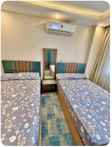two beds in a small room with a mirror at شقة فندقيه بمدينتي in Madinaty