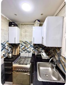 a kitchen with white cabinets and a sink at شقة فندقيه بمدينتي in Madinaty