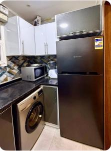 a kitchen with a black refrigerator and a microwave at شقة فندقيه بمدينتي in Madinaty +4 photos