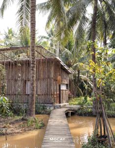 a wooden bridge over a river in front of a building at MOCAY farmstay in Ben Tre