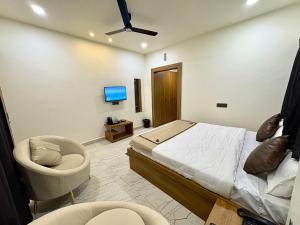 a bedroom with a bed and a chair and a tv at Hotel Sambhavi in Hisua