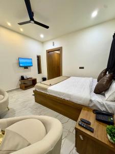 a bedroom with a bed and a couch and a tv at Hotel Sambhavi in Hisua