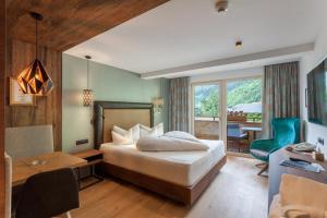 a hotel room with a bed and a desk and a table at Ferienhotel Sonnenhof in Zell am Ziller +75 photos