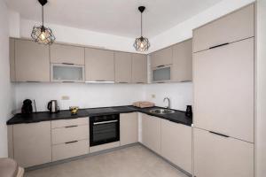 a kitchen with white cabinets and black counter tops at Bozovic Apartman 2 in Budva +3 photos