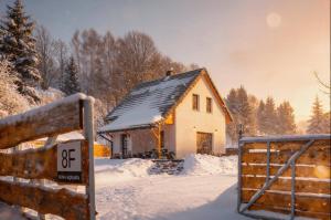 a small house in the snow with a gate at Luisówka - majestatyczny domek z jacuzzi in Stronie Śląskie