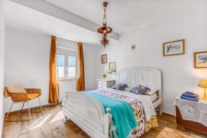 a bedroom with a white bed and a chair at O Mundo da Lua in Azeitao