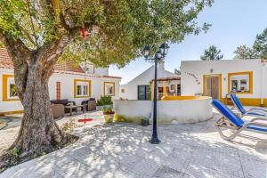 a patio with chairs and a tree and a house at O Mundo da Lua in Azeitao