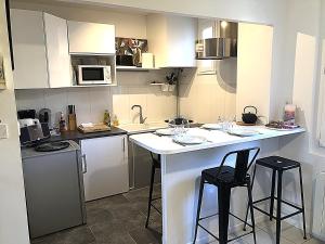 a kitchen with white cabinets and two bar stools at La Chantrerie Saint Priest in Cahors
