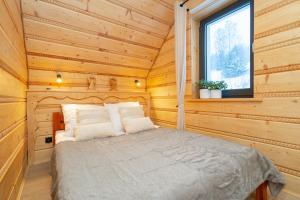 a bed in a log cabin with a window at Luisówka - majestatyczny domek z jacuzzi in Stronie Śląskie
