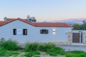 a white house with a red roof at Voidοkilia rooms in Petrochori