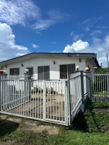 a white house with a gate in front of it at Cozy Self-contained Unit in Lautoka