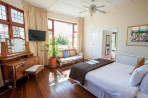 a bedroom with a bed and a desk and a television at Portview and Brenwin Guesthouse in Cape Town