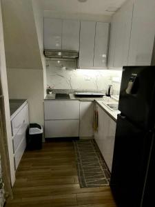 a small kitchen with white cabinets and a black refrigerator at Miyu's Staycation Place in Biñan