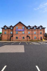 a large red brick building with a parking lot at Premier Nights, Wigan, Standish M6 J27 in Standish