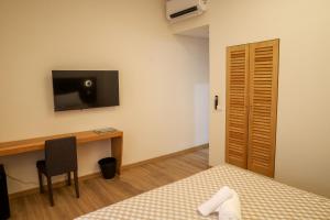 a bedroom with a desk and a tv on the wall at GUMBELA - Hotel in São Tomé +12 photos