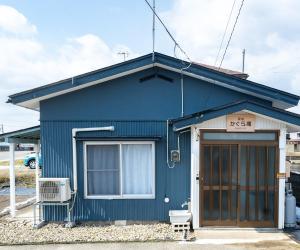 a blue house with a door and a sign on it at かぐら庵 in Kitakata