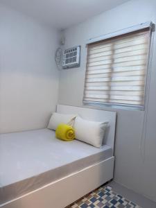 a small room with a bed with a yellow pillow at Ormoc Gdex Transient in Ormoc