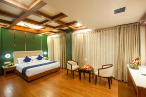 a bedroom with a bed and a desk and chairs at Hotel Gentleman Plaza in Alleppey