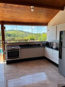a large kitchen with a large window with a view at Refúgio Bosques de Itu in Itu