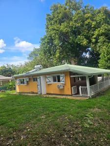 a yellow house with a green roof on a yard at Maison de vacances in Deshaies