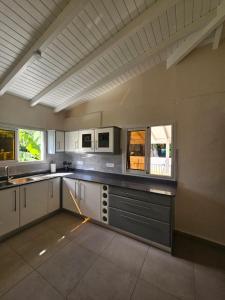 a large kitchen with white cabinets and windows at Maison de vacances in Deshaies