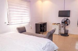a bedroom with a bed and a tv and a fan at 4 Kays Apartment in Agege