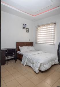 a bedroom with two beds and a desk and a window at 4 Kays Apartment in Agege