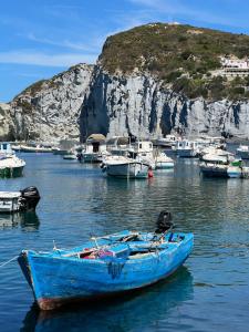 a blue boat sitting in the water near a mountain at La Cupoletta Ponza in Arcipelago Ponziano