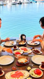 a table with plates of food next to the water at Assos Troy Port Hotel in Behramkale