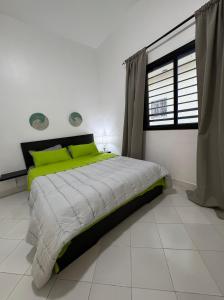 a bedroom with a bed with green pillows and a window at WHITE FLAT ALMADIES in Dakar