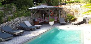 a swimming pool with chairs and a gazebo at La Belle Maison in Piégut-Pluviers