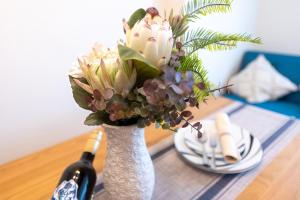 a vase filled with flowers on a table with a bottle of wine at 新宿駅まで12分渋谷駅まで22分最大8名様宿泊可能4ベッドルーム in Ogikubo