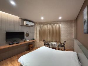 a bedroom with a bed and a table and a tv at 橙橙民宿瑞芳車站 in Ruifang