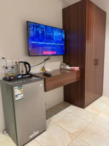 a desk with a television and a refrigerator in a room at شقق أريز ستاي in Al Hada