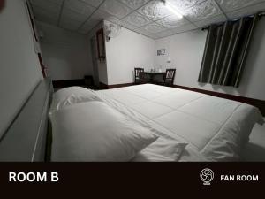 a bedroom with a large bed with white sheets at Huean Him Pan Homestay เฮือนฮิมปานโฮมสเตย์ in Ban Mae Pan