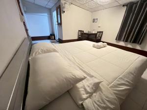 a bedroom with a large bed with white sheets at Huean Him Pan Homestay เฮือนฮิมปานโฮมสเตย์ in Ban Mae Pan