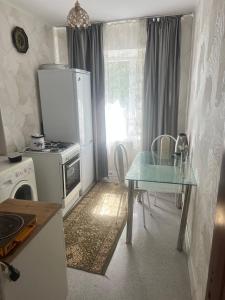 a kitchen with a glass table and a kitchen with a stove at Квартира у Асели in Karakol