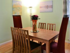 a dining room table with a vase with flowers in it at Harbour View in Oban
