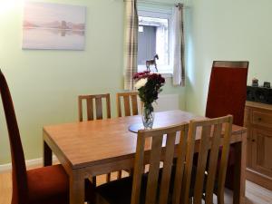 a dining room table with a vase of flowers on it at Harbour View in Oban