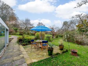 a table with a blue umbrella in a garden at Highlands Farmhouse in Dallington
