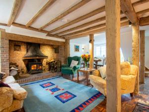 a living room with a fireplace and a green chair at Highlands Farmhouse in Dallington