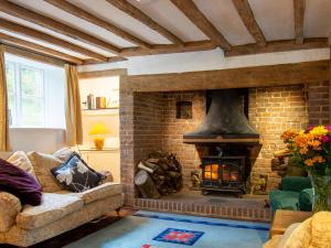 a living room with a brick fireplace and a couch at Highlands Farmhouse in Dallington