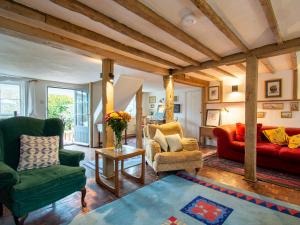 a living room with green chairs and red couches at Highlands Farmhouse in Dallington +28 photos